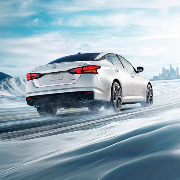 2027 Nissan Altima in white seen from behind driving in snowy landscape illustrating all-wheel drive at Holler Nissan St. Andrews in Columbia SC
