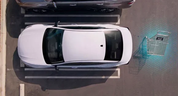 Top view of a white 2027 Nissan Altima in a parking lot with rear sensors detecting a shopping cart behind it at Holler Nissan St. Andrews in Columbia SC
